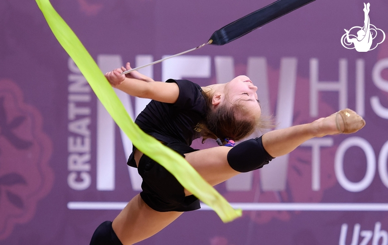 Ксения Савинова выполняет прыжок в шпагат во время упражнения с лентой на опробовании