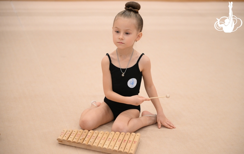 Юная гимнастка во время занятия ритмикой