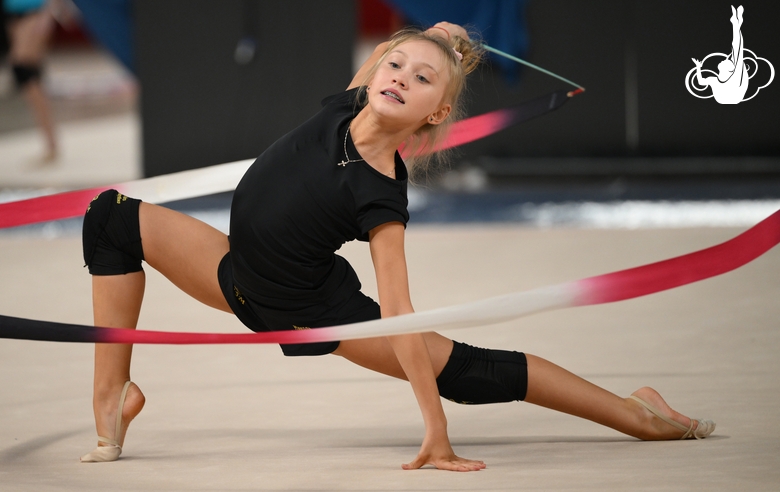Гимнастка во время упражнения с лентой на опробовании ковра в Академии единоборств