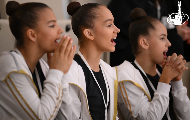 Гимнастки поддерживают других участниц на трибуне